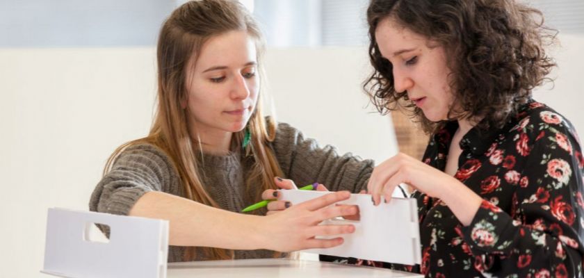 Deux étudiantes en train de positionner les éléments d'un tabouret en carton.