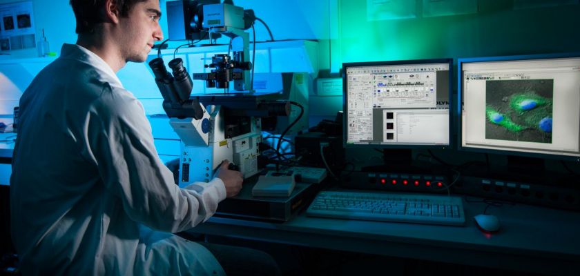 homme en blouse devant un microscope