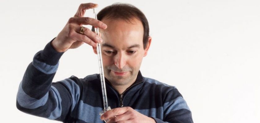 Portrait de Stéphane Roux avec des accessoires de chimie.