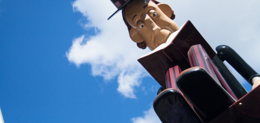 Vue en contre plongée d'un personnage sculpté qui lit un livre sur un ciel bleu