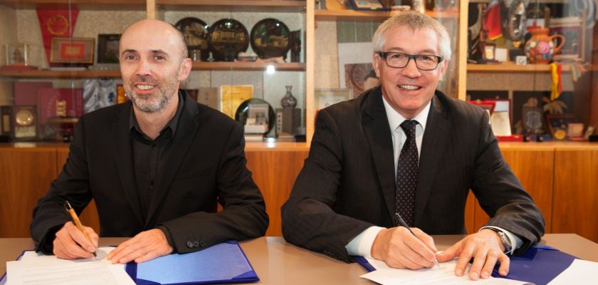 Les mains de deux personnes en costume lors d'une signature officielle.