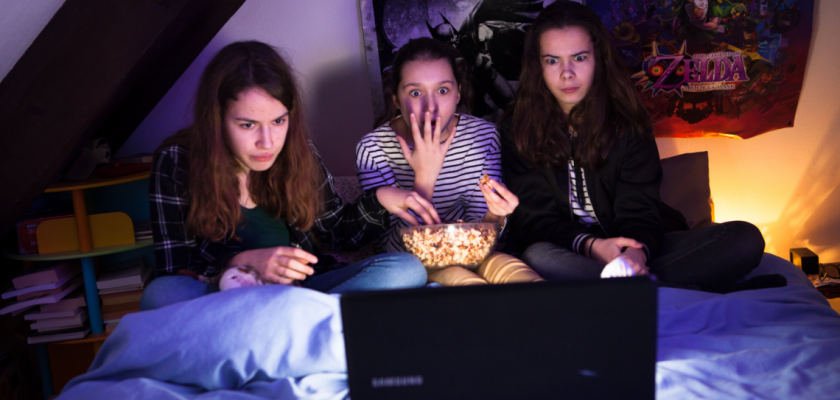 Trois adolescentes en train de regarder un film et de manger du popcorn