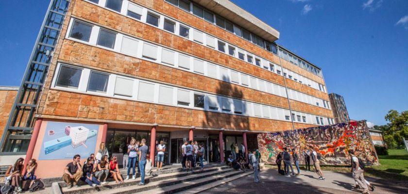 Vue extérieure d'un bâtiment orange avec de nombreux étudiants devant.