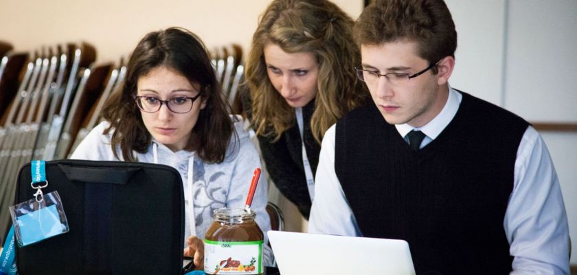 Trois étudiants l'air préoccupé devant leurs ordinateurs portables avec un pot de pâte à tartiner au milieu.