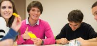 Trois lycéens souriant lors d'un atelier de pliages géométriques. 