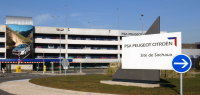 Vue extérieure du site PSa de Sochaux avec une pancarte de signalisation.