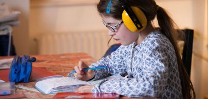 Une fillette fait ses devoirs avec un casque anti-bruit sur les oreilles.