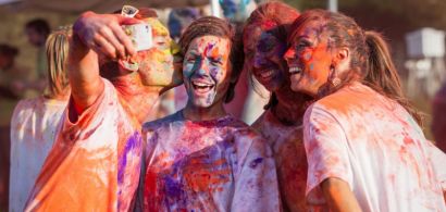 Quatre étudiants recouverts de farine colorée en train de faire un selfie.