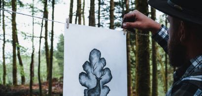 Kiven B affichant en forêt une de ses créations graphiques