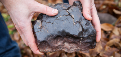 Des mains tenant un morceau de météorite