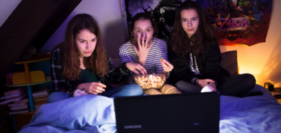 Trois adolescentes en train de regarder un film et de manger du popcorn