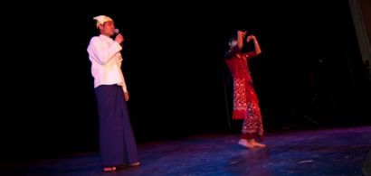 Deux personnes chantent et dansent en costume traditionnel.