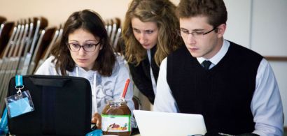 Trois étudiants l'air préoccupé devant leurs ordinateurs portables avec un pot de pâte à tartiner au milieu.