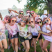 Un groupe d'étudiants avec des lunettes de soleil et couverts de poudre colorée posent en groupe.
