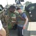 Un militaire aide un étudiant à enfiler un gilet de munitions