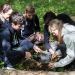 Un groupe d'étudiants accroupis prélèvent de la terre avec une petite pelle.