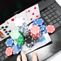 Des jetons de poker, cartes à jouer et billets posés sur un ordinateur portable